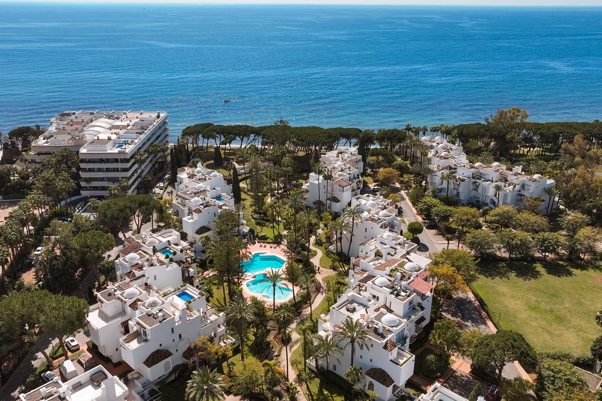 Aerial view of the gated Alhambra del Mar community on Marbella's Golden Mile with lagoon pools, palm gardens and the Mediterranean beyond